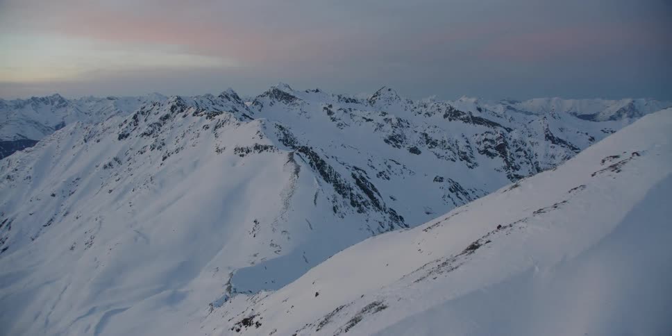The mountains are covered with heavy snow on a cloudy day