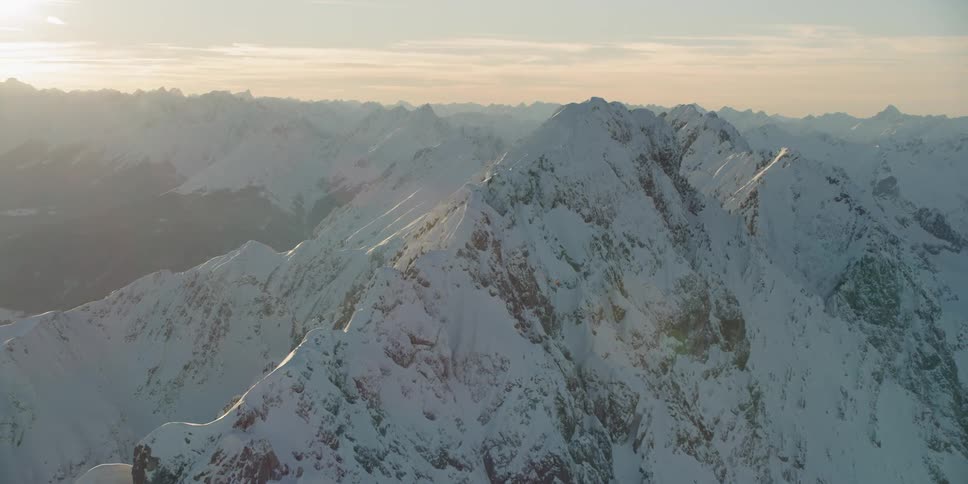 The sun sets over snowy mountains