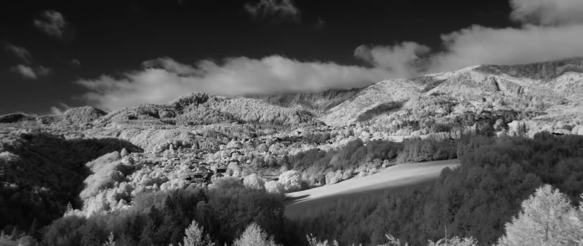 Clouds float above mountains and trees