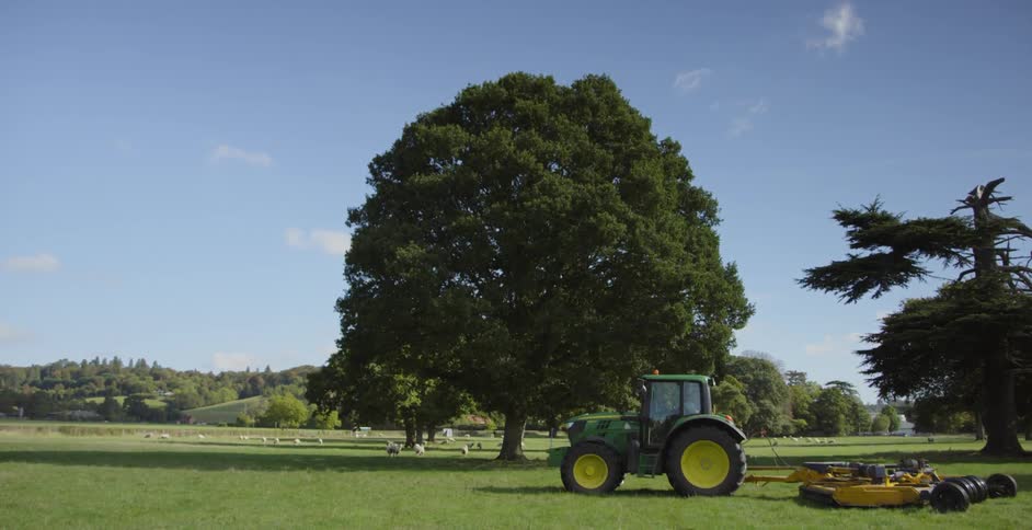 A tractor pulls a mower on the grass field