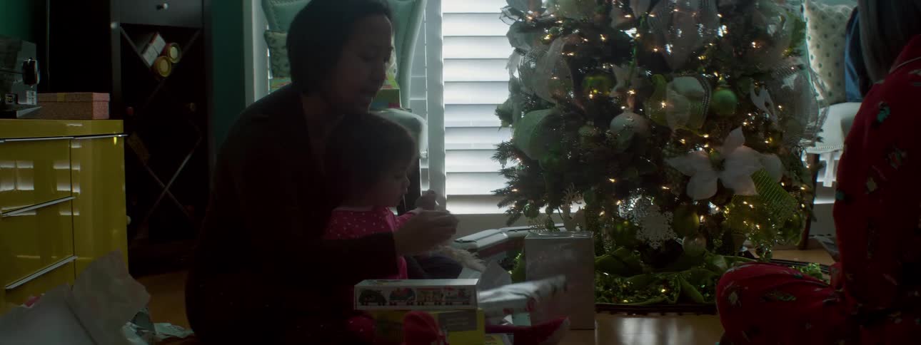 A woman opens christmas gifts with a child