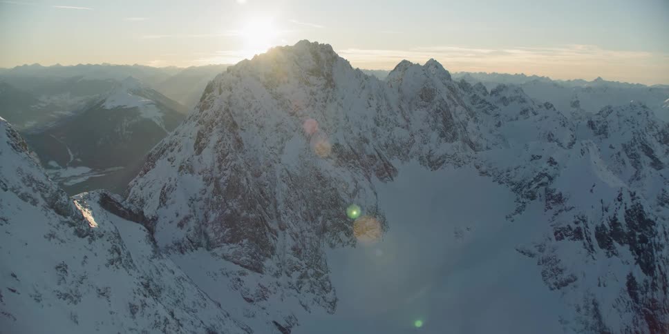 Sunlight is streaming onto a mountain range covered in snow