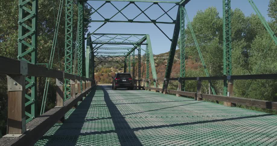 A jeep drives over a bridge