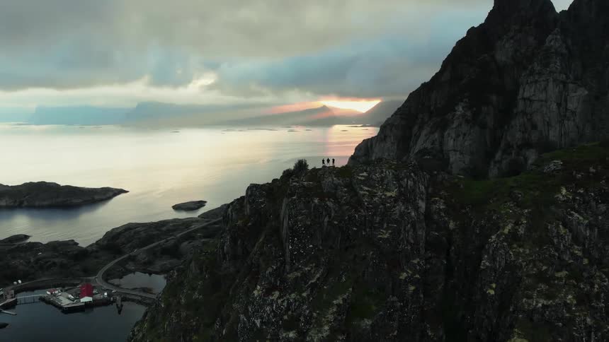 Hikers stand on a mountain peak at sunset