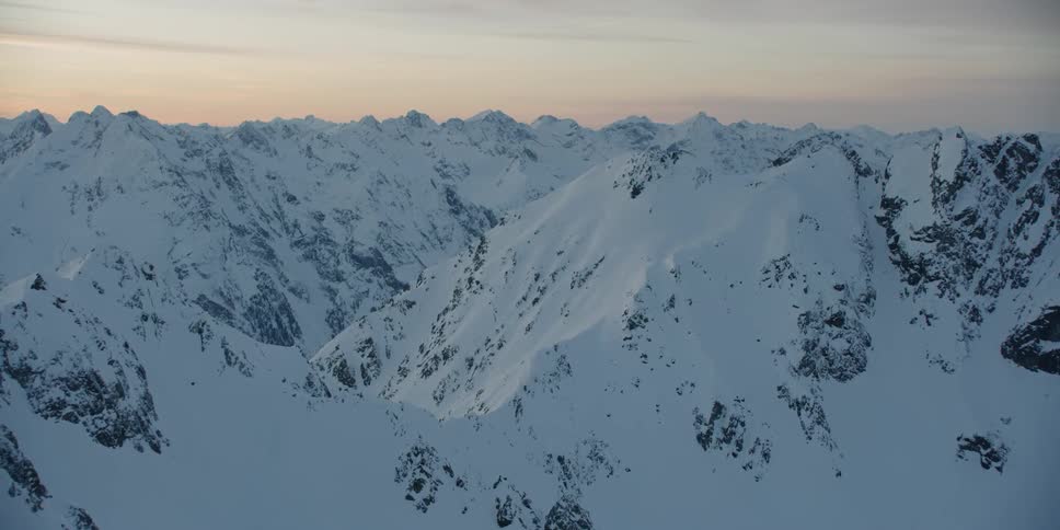 The sun sets over snowy mountains