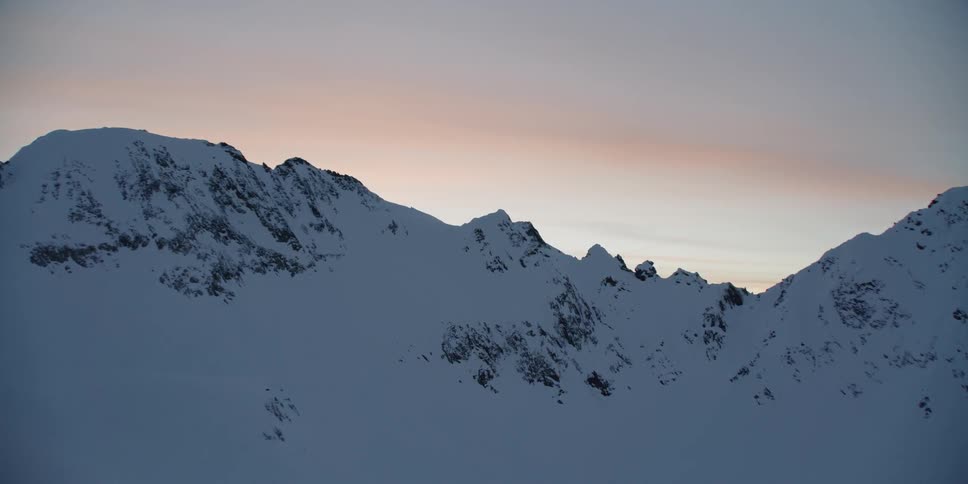 Snow covered mountains at sunset with clouds in the sky