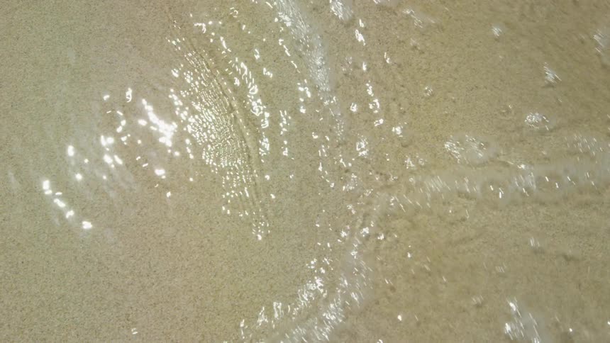 Waves flow over a sandy beach