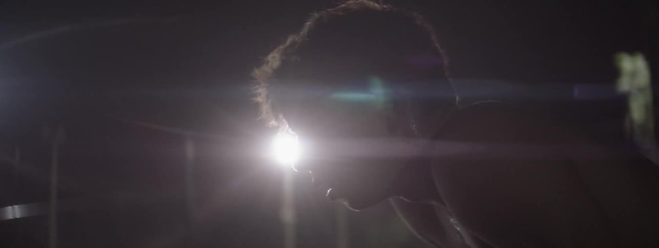 Man plays tennis on an outdoor court at night