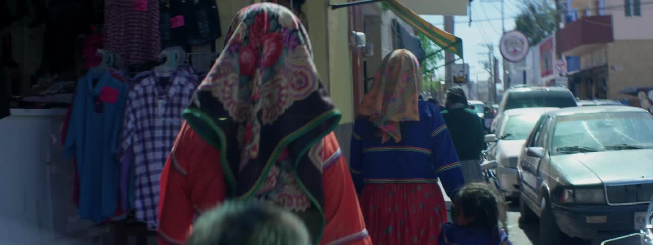 Two women walk with children on the sidewalk