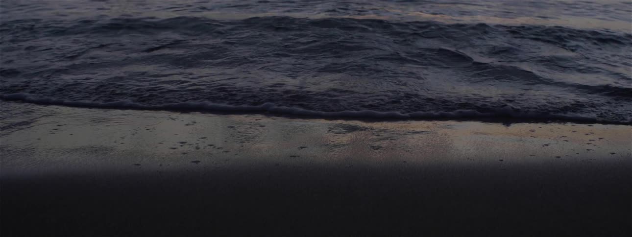 Ocean waves flow on the beach at sunset