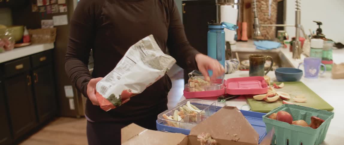 A woman packs lunches for children