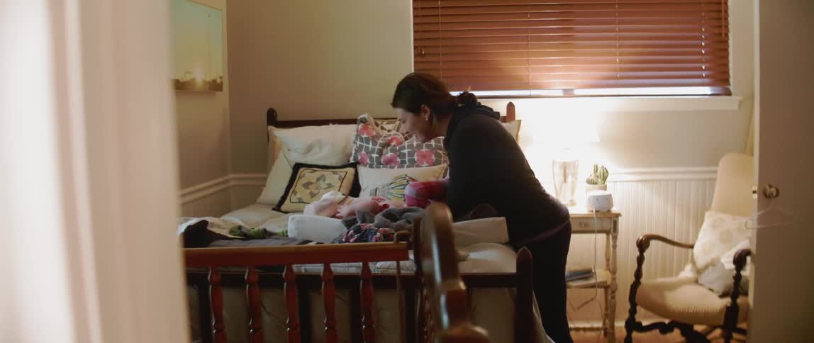 Woman plays with a baby on a bed