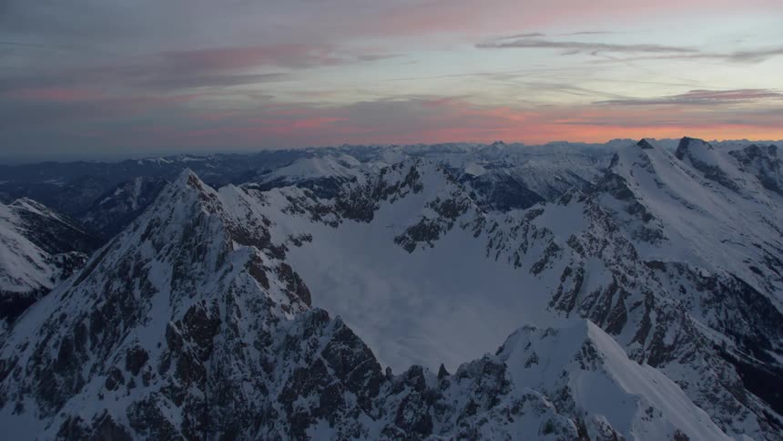 The sun sets over snowy mountains