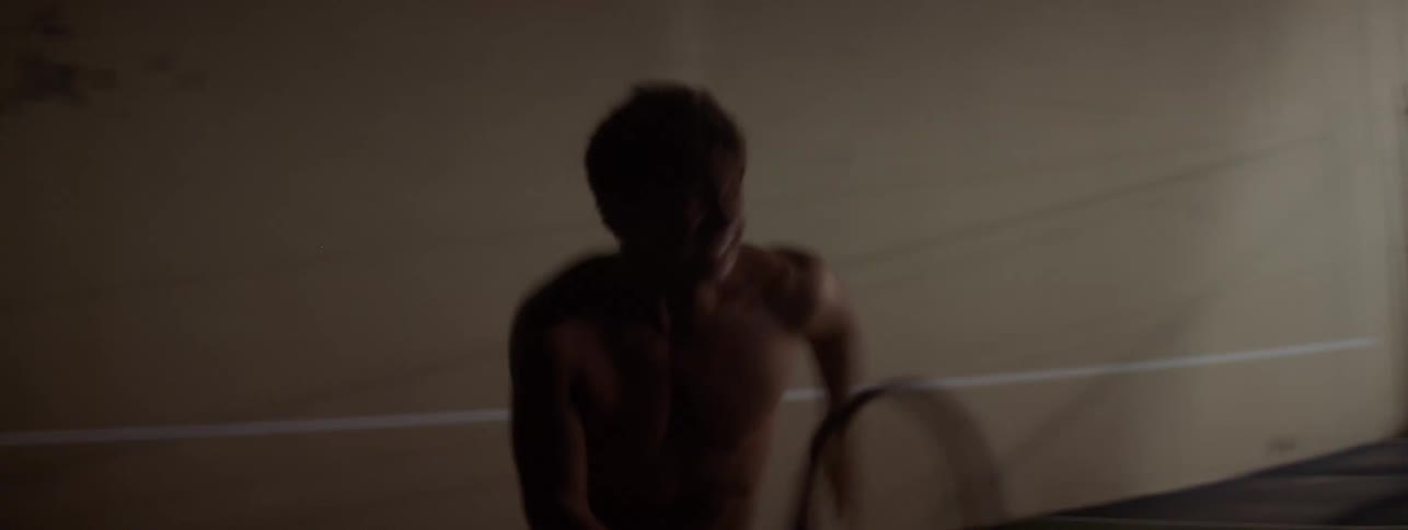 A man runs back and forth on the tennis court at night