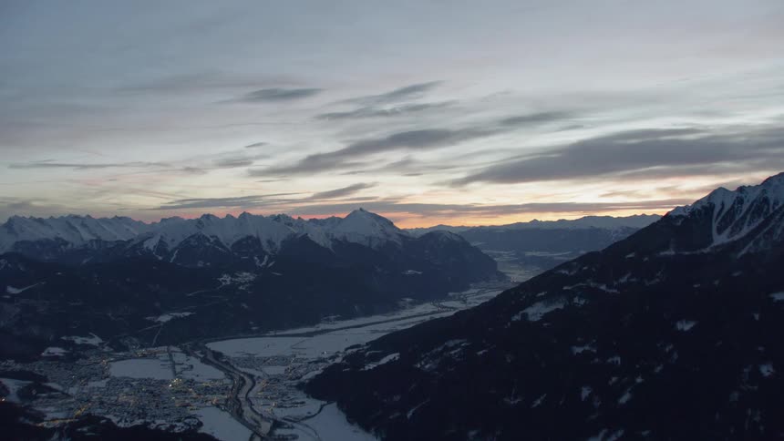 The sun sets over snowy mountains