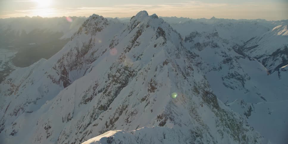 The sun sets over snowy mountains