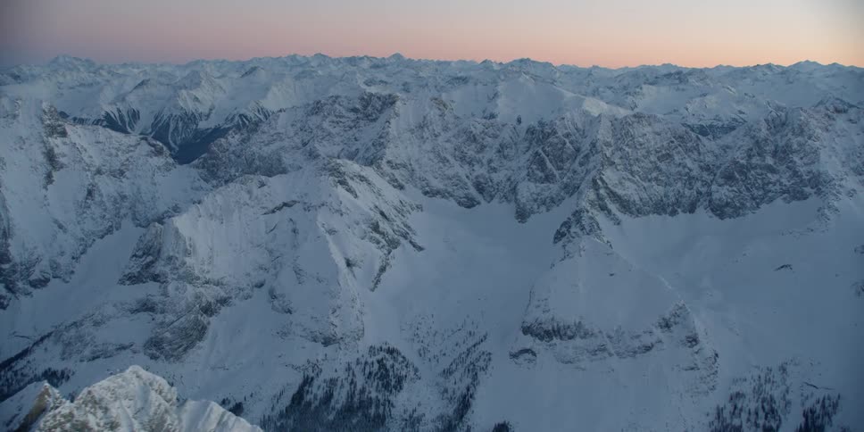 The sun sets over snowy mountains