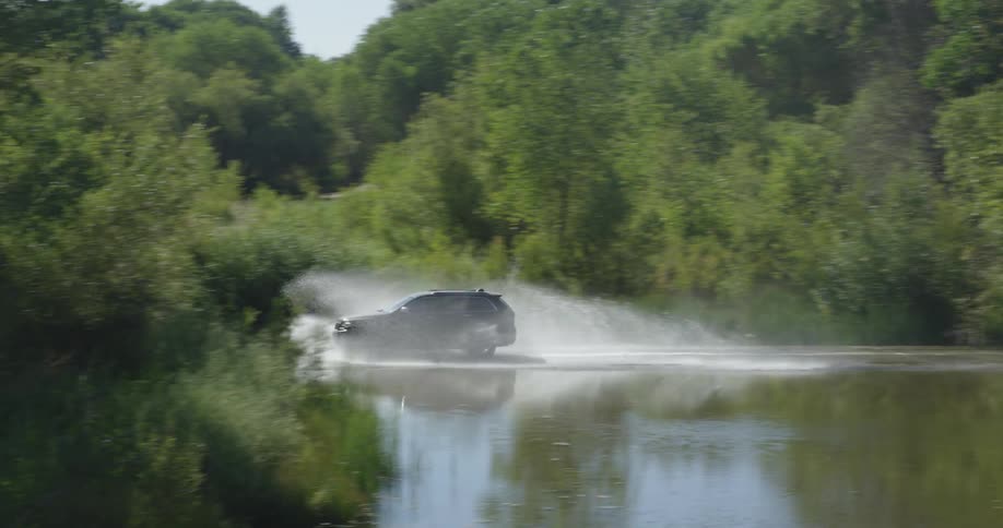 An suv splashes water as it travels over a flooded road