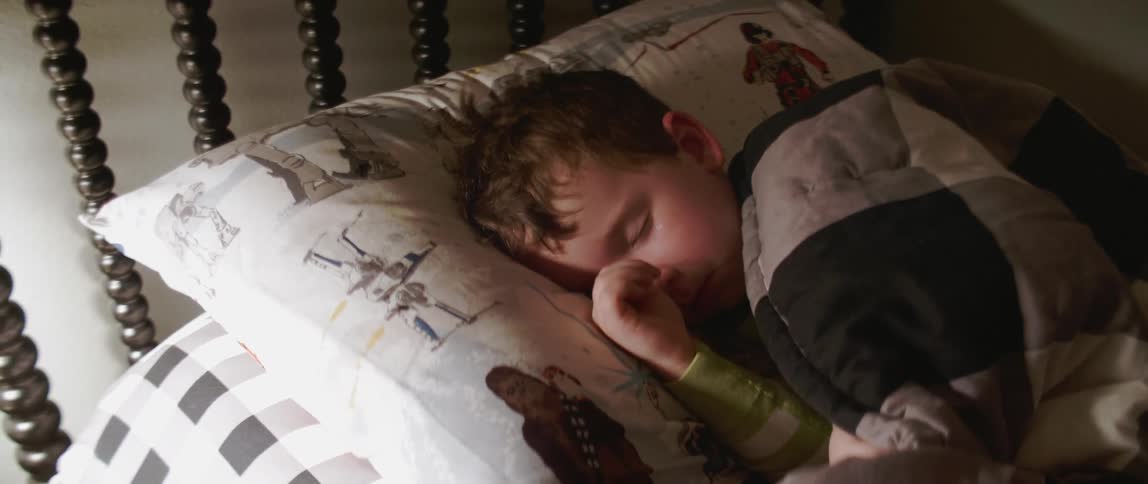 A young boy rubs his eye while sleeping