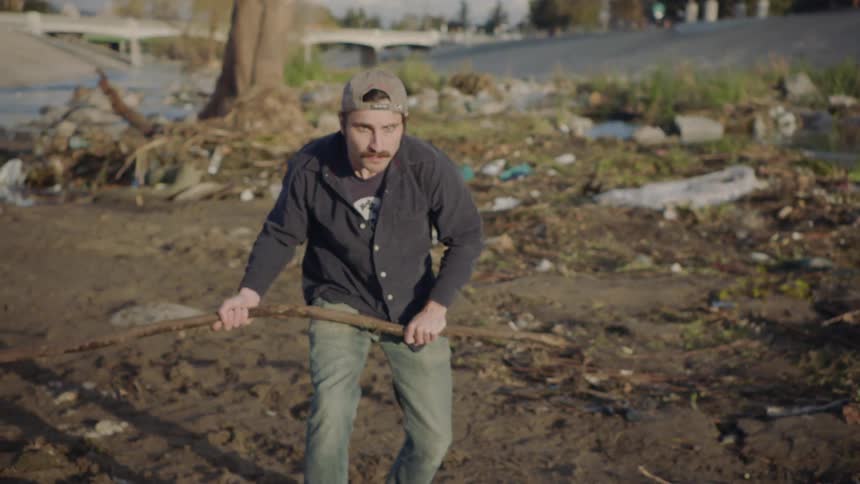 A man picks up a stick and swings it at someone