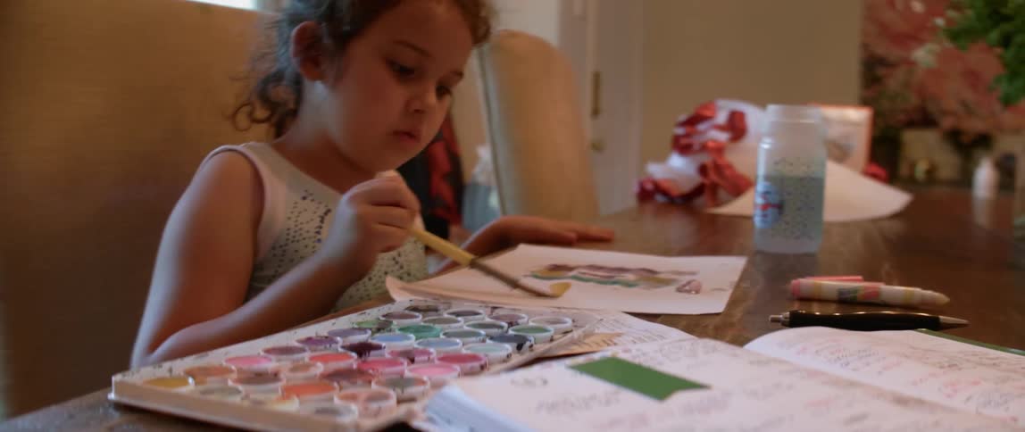 A young girl paints on the table