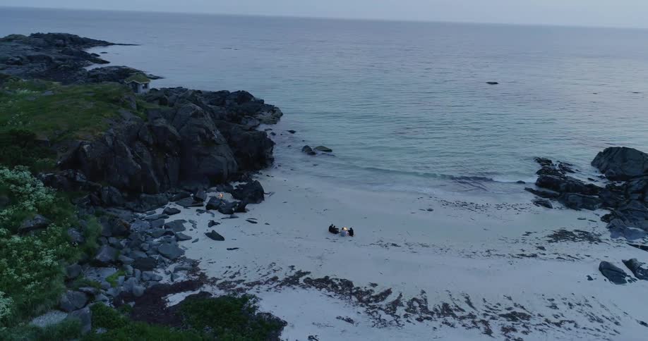 People sit on a beach at sunset