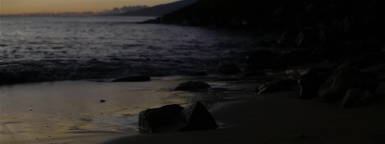 The waves splash against the shore at dawn