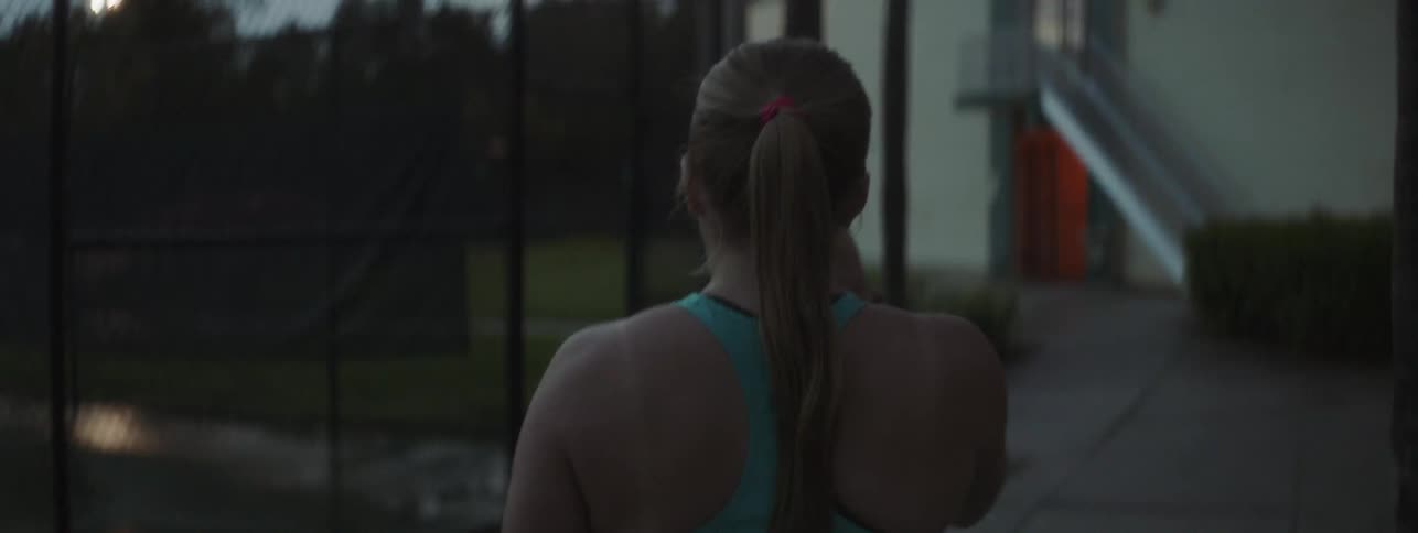 A woman walks towards the tennis court