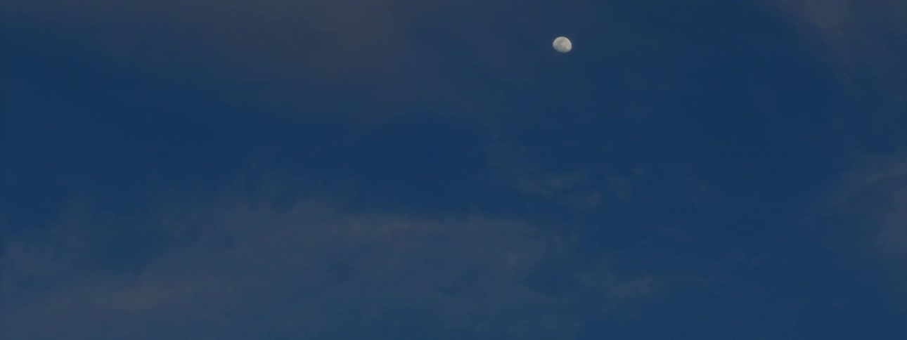 Clouds float near the moon in the sky