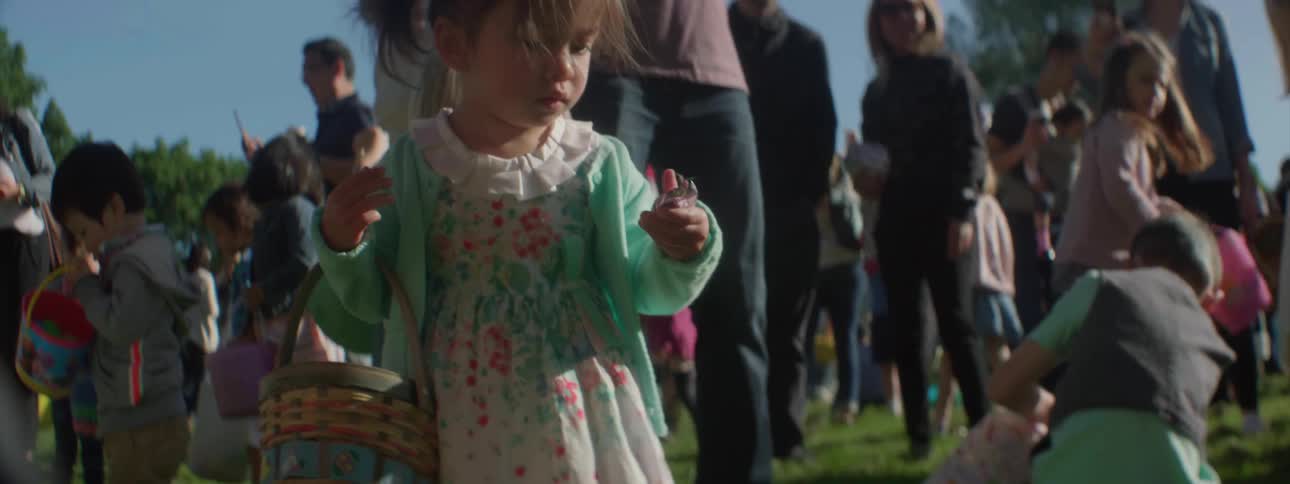 A girl pulls the prize out of a plastic egg during an easter egg hunt