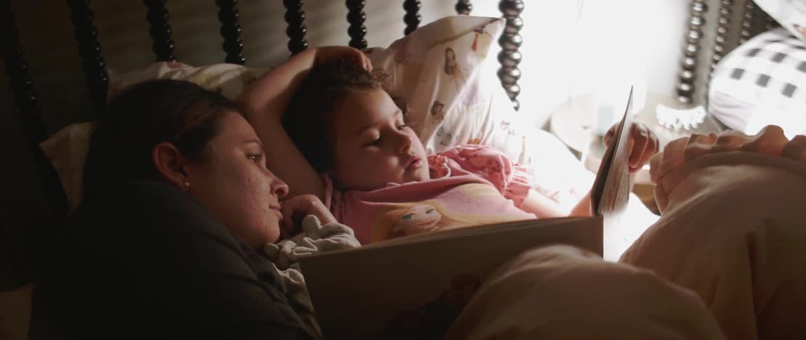 Woman and child lay in bed reading a book