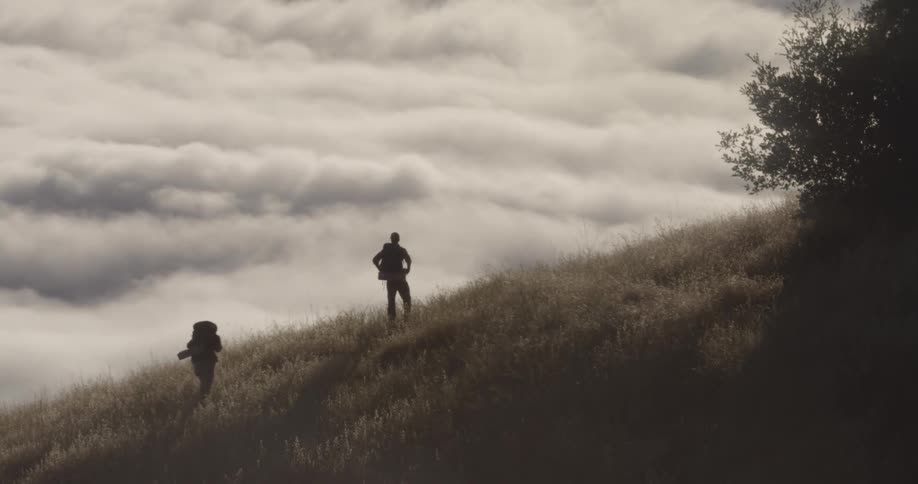 Hikers walks up a grassy hillside