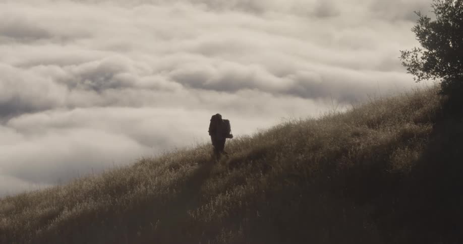 Two men walk down a grassy hill
