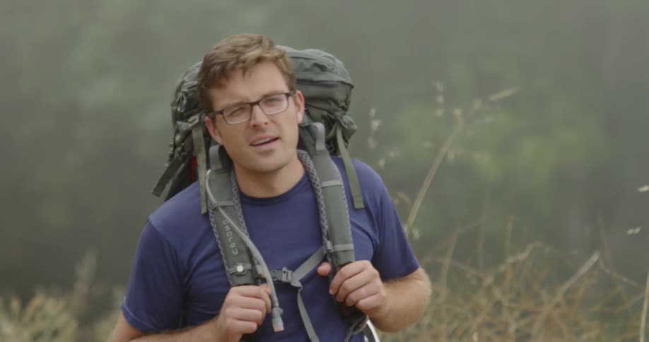 Man with a backpack hikes through tall grass