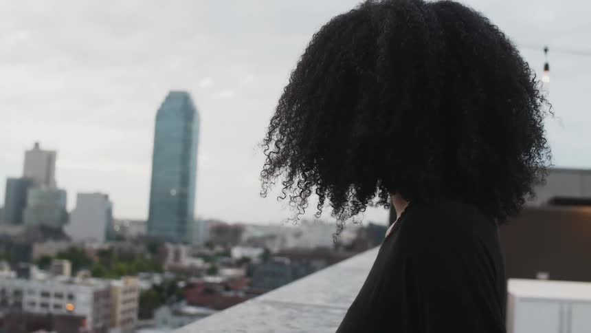 A woman is standing on the roof of a building and looking over the city