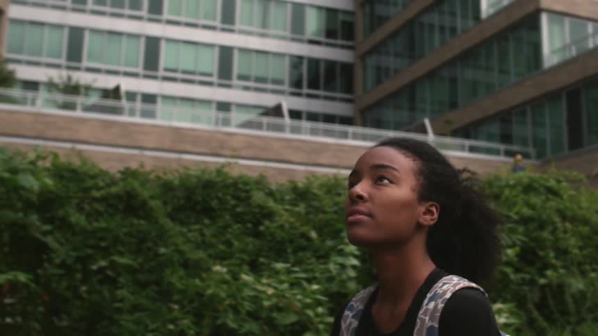 Woman walking by a building looking up