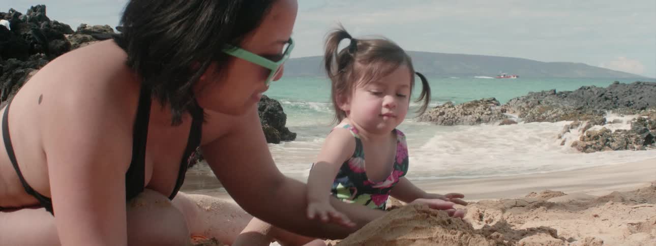 A mom and her daughter are making a sand castle on the beach
