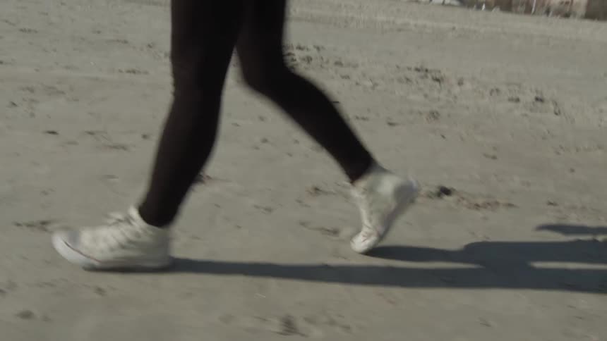 Person's legs walking quickly over the sand