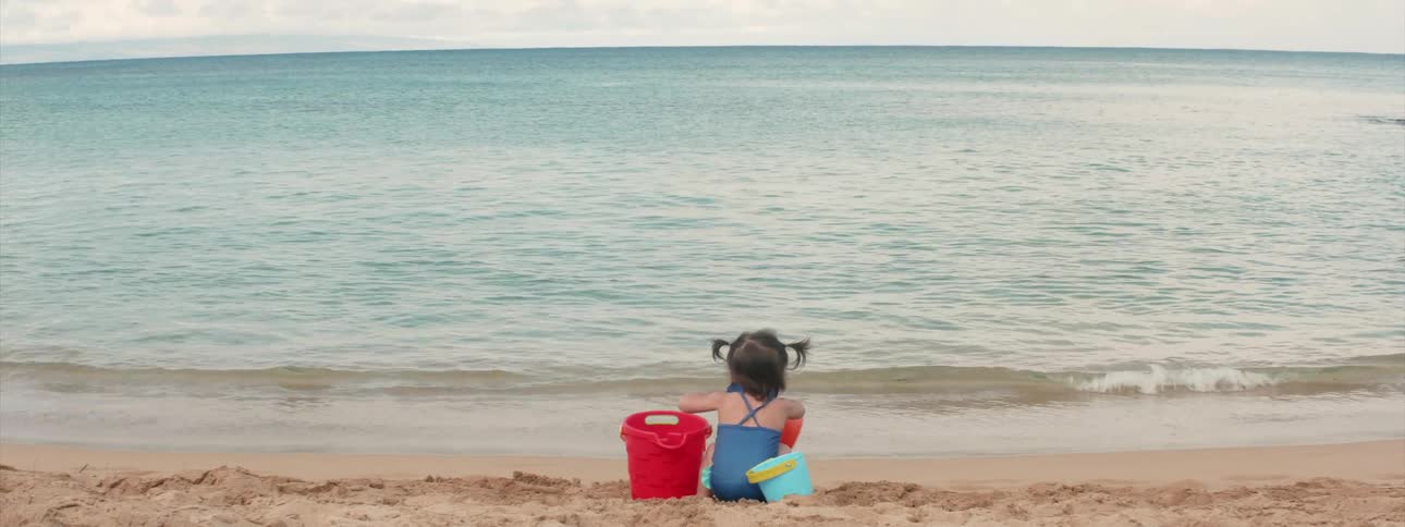 A child is playing with buckets near the beach water