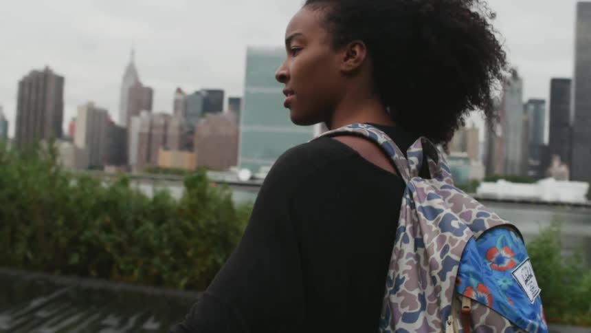 Girl walking along the water with buildings across the way