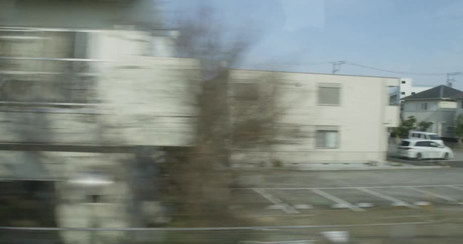 A train is passing by residences and buildings near its tracks in daylight