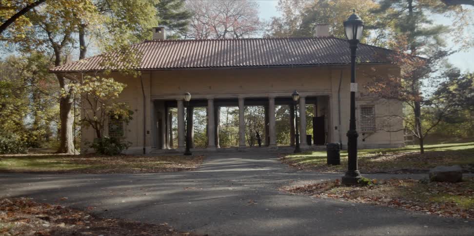 A person is walking into the center of a monument building in a park in daylight