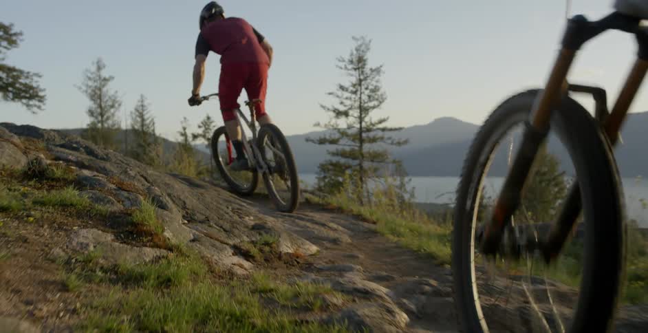 Two men ride bicycles on a hilly path