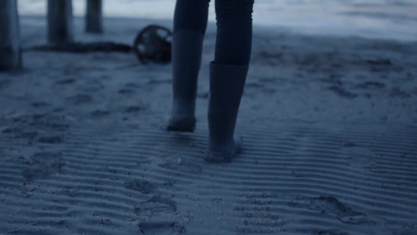Someone is walking in boots on the beach towards the water