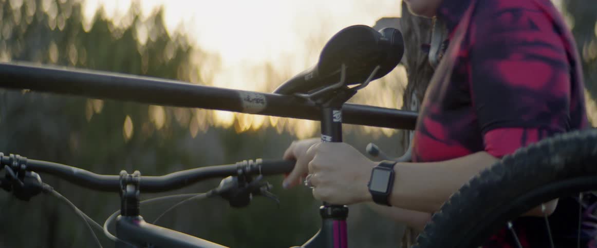 A woman lifts her bicycle off the rack on the tree