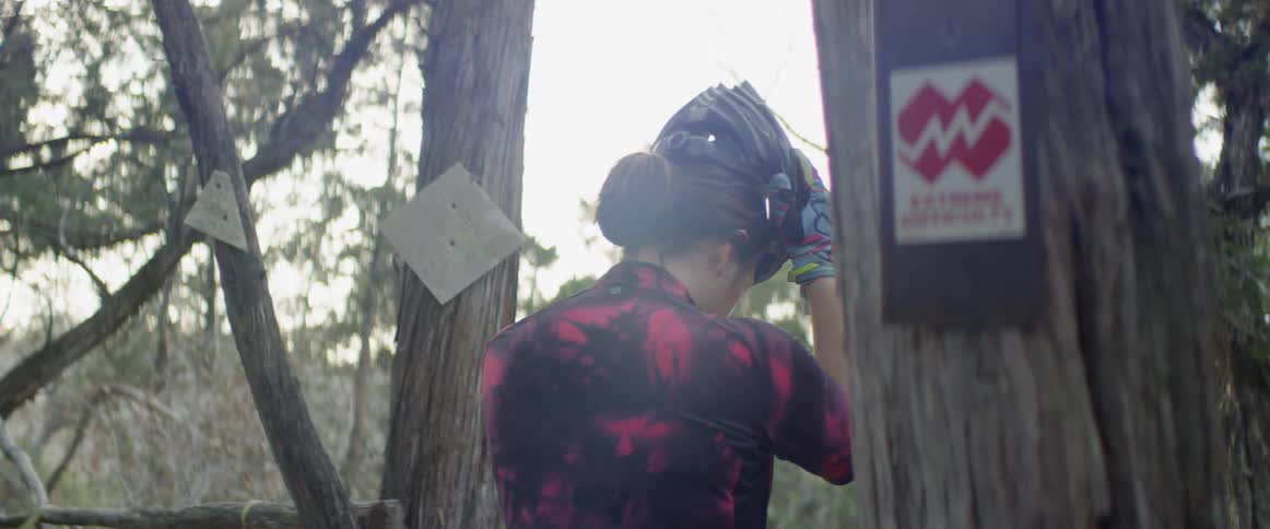 A woman puts on a helmet outdoors
