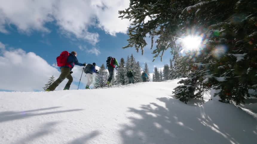 Group of people hiking up snow covered mountain on cloudy day