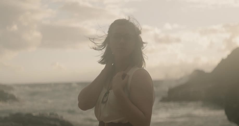 Woman stands on a beach at sunset