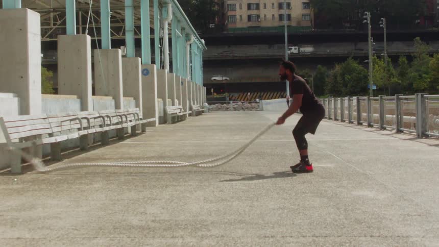 Man slaps two large ropes on the ground