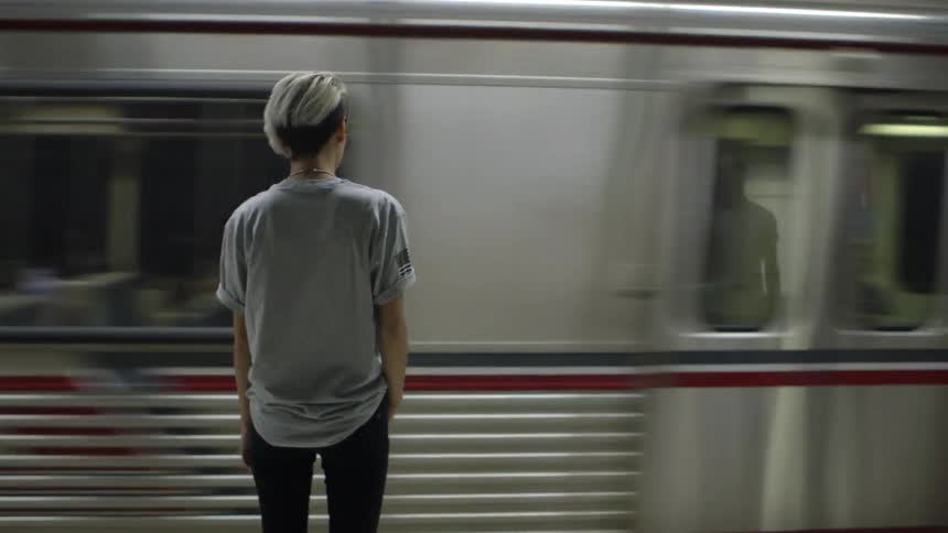 A young woman standing on a train platform as the commuter train goes by